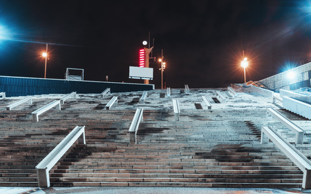 Wide-angle night view of a wide contemporary staircase with concrete railings for skating; a broad...