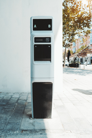 Outdoor power supply station of black and white colors for electric car charging; electric vehicle charging station for public usage in the shadow of Barcelona street, Spainの写真素材