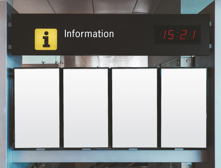 Close-up information or arrival and departure board mockup consisting of four blank white vertical LDC screens with time board above in an airport terminal or a railway station depotの写真素材