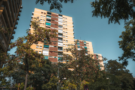 Wide-angle view of the row of ordinary dwelling houses framed by trees in a residential district of...