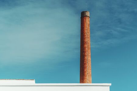 View of a red brick funnel behind a partly visible white wall with the lightning-rod on the top and the sky in the background, Lisbon, Portugalの写真素材