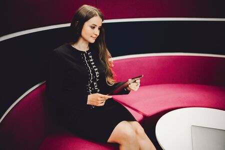 A young charming caucasian woman entrepreneurÂ with a long hair is sitting on the curved modern...