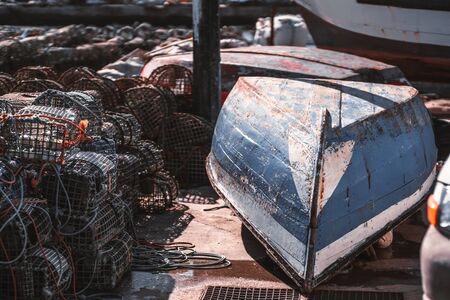 Inverted wooden boat on a pier surrounded by many fishing traps for crab and seabed dwellers; the fishing cog laying upside down with fishing tackle around on a sunny day, Cascais, Portugalの写真素材
