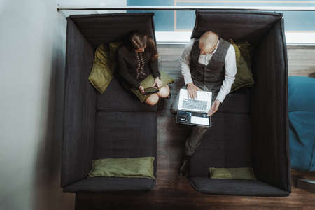 View from above of two successful business people in a cozy co-working area of a modern office...