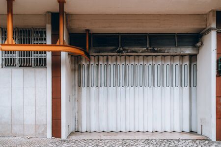Front wide-angle view of a modern vertical folding white gate in a residential building or gates of...