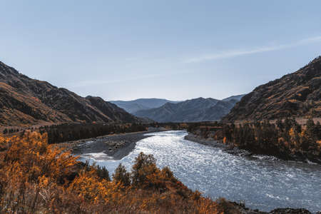 A stunning fall mountain scenery with a blue river in the middle surrounded by ridges, yellowed...