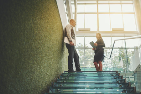 A scene with a glass staircase in the interior of a modern office skyscraper with two business...