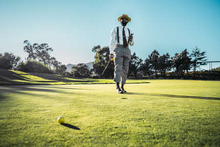 A fashionable good-looking mature bearded black guy in pants with suspenders and a straw hat, with a...