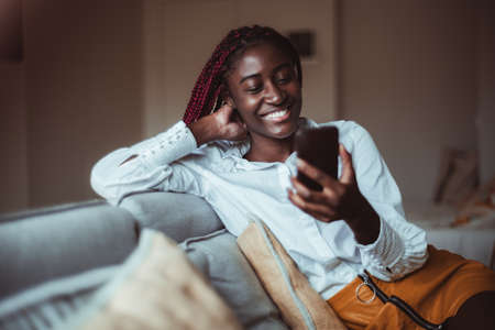 Portrait of a young cheerful African-American woman with red braids having a phone video...