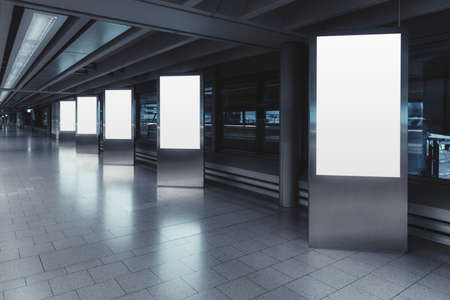 Five empty vertical posters mock-ups glowing with a LED neon light in an airport terminal; a group of blank banners templates in a corridor of a shopping mall; mockups of 5 indoor billboards in a hallの写真素材