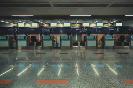 A row of empty check-in cabins in an international airport with small blank LCD screens mockups....