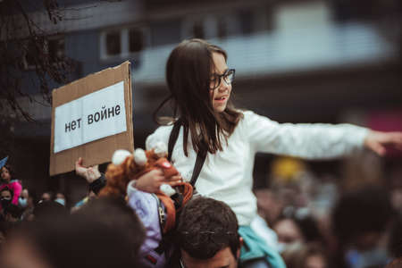 Lisbon, Portugal - February 27, 2022: a true tilt-shift shot of a smiling Portuguese girl sitting on the shoulders and the poster "No War" in Russian, during a protest against the invasion of Ukraineのeditorial素材
