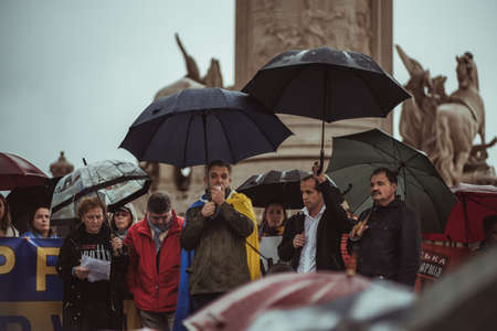 Lisbon, Portugal - March 20, 2022: a protest action in support of Ukraine, against Russian invasion and aggressive war: a stage with protesters with umbrellas under the heavy rain, man using megaphoneのeditorial素材