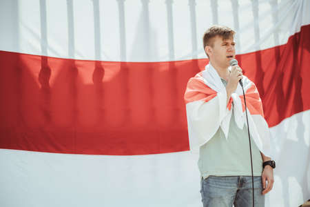 Lisbon, Portugal - March 19, 2022: a Belorussian protest action in support of Ukraine, against Russian invasion and aggressive war: stage with a young man speaking into a microphone; Byelorussian flagのeditorial素材