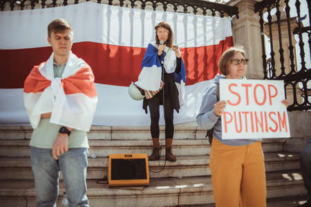 Lisbon, Portugal - March 19, 2022: a Belorussian manifestation in support of Ukraine, against invasion and aggressive war: selective focus on a woman speaking into a microphone in the backgroundのeditorial素材