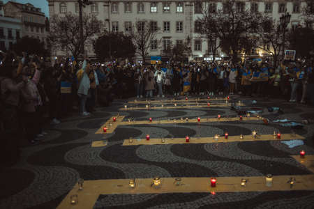 Lisbon, Portugal - April 20, 2022: a night protest rally dedicated to saving the Ukrainian city of Mariupol; burning candles in memory of the dead; people shine their cell phone flashlights upのeditorial素材