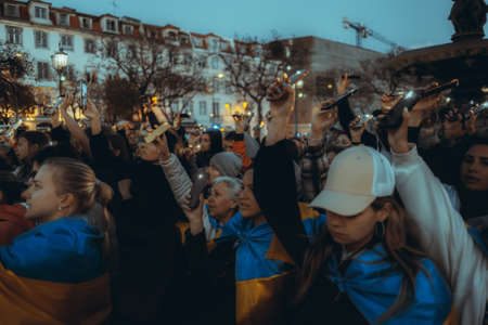 Lisbon, Portugal - April 20, 2022: a night protest manifestation dedicated to saving the Ukrainian city of Mariupol which was almost destroyed by Russia; people shine their cell phone flashlights upのeditorial素材
