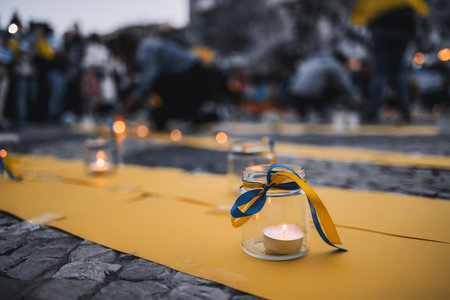 Lisbon, Portugal - April 20, 2022: lit candles wrapped in ribbons in the colors of the Ukrainian flag, in memory of those who died in Mariupol during a protest rally in saving Mariupolのeditorial素材