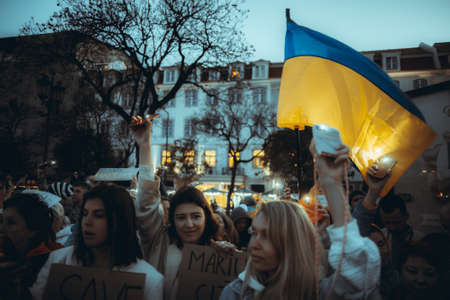 Lisbon, Portugal - April 20, 2022: a night protest action dedicated to saving the Ukrainian city of Mariupol which was destroyed by Russian militaries; people shine their cell phone flashlights upのeditorial素材