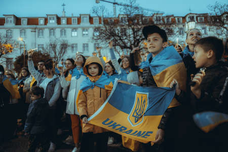 Lisbon, Portugal - April 20, 2022: protest rally dedicated to saving the Ukrainian city of Mariupol from the Russian troops; protesters with flashlights, a group of children holding the Ukrainian flagのeditorial素材