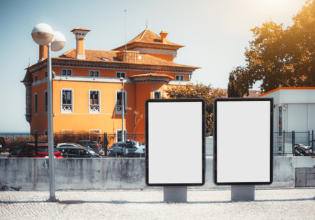Two empty mock-ups of street advertising billboards on the pavement; two blank ad placeholders outdoors; template of outdoor advert posters on the paving stone in front of an orange houseの写真素材