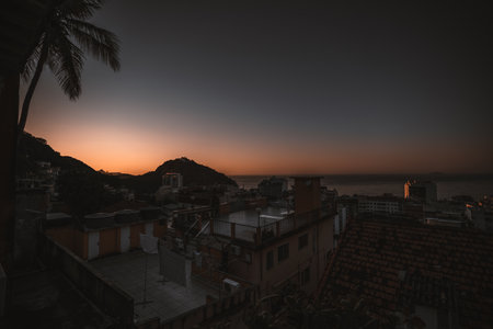 A wide-angle sunset shot from a rooftop in a house placed in a Brazilian favela in Rio, overlooking...