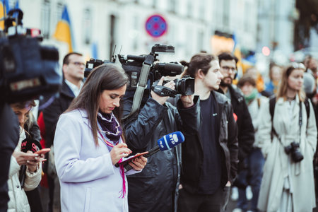 Lisbon, Portugal - February 24, 2023: A throng of protesters at a Ukrainian war anniversary; cameras rolling and reporters filming with equipment capturing the historic moment making it memorableのeditorial素材