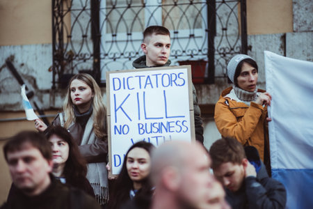 Lisbon, Portugal - February 24, 2023: Young protestors united on the one-year anniversary of the Ukrainian war; a young man holds a cardboard sign bearing a powerful anti-war messageのeditorial素材