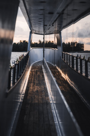 A vertically shot from a boat's deck is a unique capture of a sunset mirrored by the wall of the boat, the serene seascape in the background in shallow depth of field is beautifulの写真素材