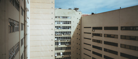 A panoramic view of humble suburban apartments in Rio de Janeiro; their cream color radiates warmth and the square windows, each equipped with air conditioning, provide a glimpse into people's lives thereの写真素材