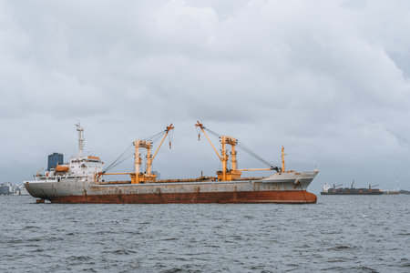 A cargo ship in the serene seas, its worn exterior showing signs of sea erosion, as it carries vital supplies to the bustling city port. Waves crash against its hull, but the journey must go onの写真素材