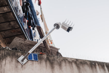 Lisbon; Low angle shot of a white outdoor security camera surveilling attached to a very old and...