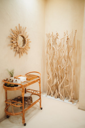 Vertical shot of a rustic-inspired house in Barcelona. Beige walls, wooden elements, and the mirror create warmth. A rattan coffee table with decorative items, and herbs add a natural touchの写真素材