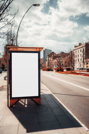 A vertical shot of a contemporary bus stop in Barcelona with a blank mock-up of an advert banner; an asphalt road with a modern transport station and an empty advertising billboard templateの写真素材