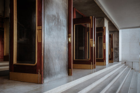 A close-up view of an elegant entrance with multiple wooden glass doors featuring brass handles and...
