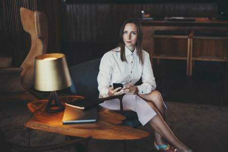 A professional woman in a white shirt and light purple skirt sits in a modern office setting,...
