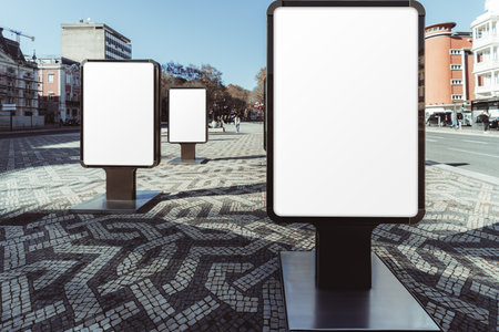 Mockup of three blank vertical billboards in an outdoor urban setting with a cobblestone mosaic pattern pavement. The empty poster stands are aligned in a row, for advertising or promotional contentの写真素材