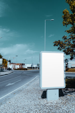 A blank vertical outdoor advertising billboard mockup on a modern street corner with a clean pavement. Ideal for displaying promotional content or branding campaignsの写真素材