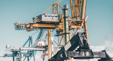 Industrial port cranes with steel structures, cables, and machinery under a clear sky. Heavy-duty equipment for container loading and unloading in a shipping terminalの写真素材