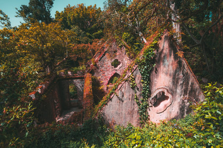Enchanted ruins of an old stone building in the forest of Sintra, Portugal, overgrown with ivy and...