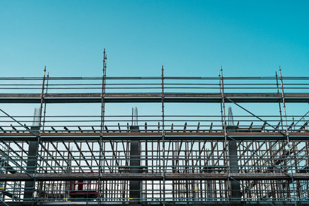 Metal scaffolding structure on a construction site under clear blue sky, showcasing architectural...