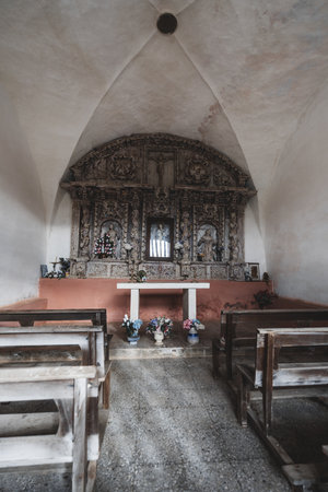 Small rustic chapel (capilla) interior along the Camino de Santiago, featuring a carved wooden...
