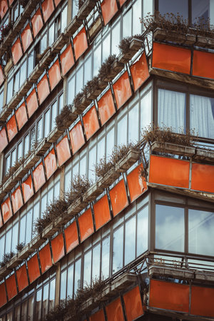 A bold modernist building in Tineo, Spain. Its glass facade, vivid orange balconies, and rhythmic rectangular structure reflect mid-century design in a small rural townの写真素材
