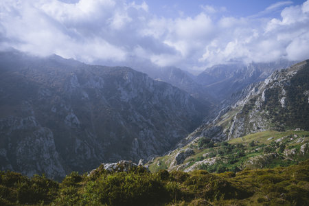 Dramatic view of Picos de Europa mountain range with rugged limestone peaks, deep valleys, and...