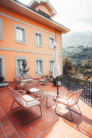 Bright orange hotel terrace with modern outdoor furniture and terracotta tiles, offering a peaceful mountain view surrounded by nature in rural northern Spain under soft daylightの写真素材