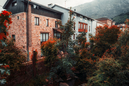 Picturesque traditional houses in Cabrales, Asturias, Spain, nestled among lush trees with autumnal...