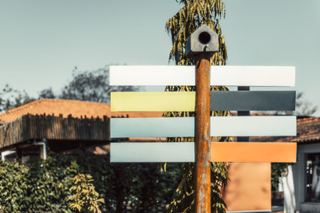 Colorful blank directional sign mockup with empty panels on a wooden pole under bright daylight, perfect template for travel, tourism or navigation design in outdoor environmentの写真素材
