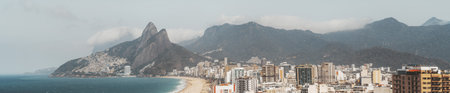 Telephoto panoramic view of Rio de Janeiro coastline with Ipanema and Leblon beach, Vidigal favela on hillside, Atlantic ocean, city skyline and mountains under cloudsの写真素材