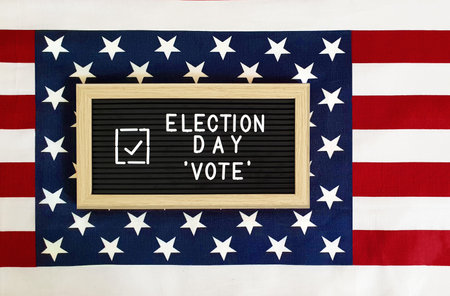 Happy Election Day letter board with Vote check mark against American flag background. Don't forget...