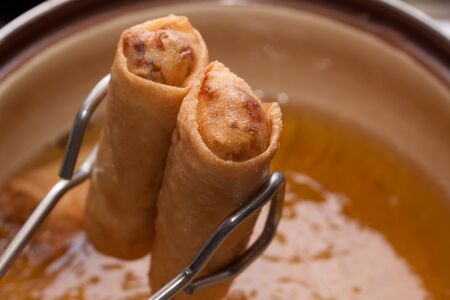 Spring roll with edible oil and pliersの写真素材